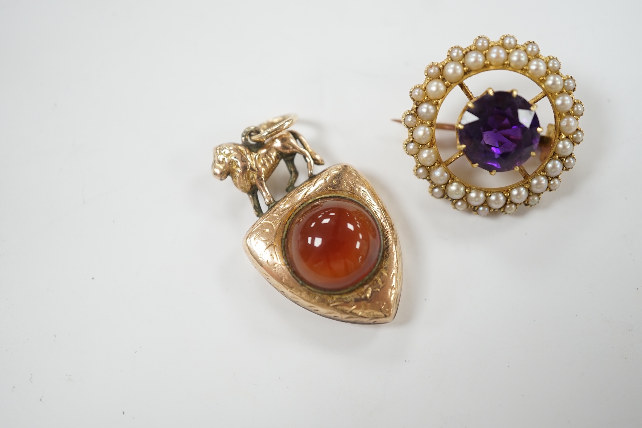 A Victorian yellow metal and two sided chalcedony set shield shaped pendant, with lion surmount, 31mm, together with an early 20th century yellow metal, amethyst and split pearl set circular brooch.